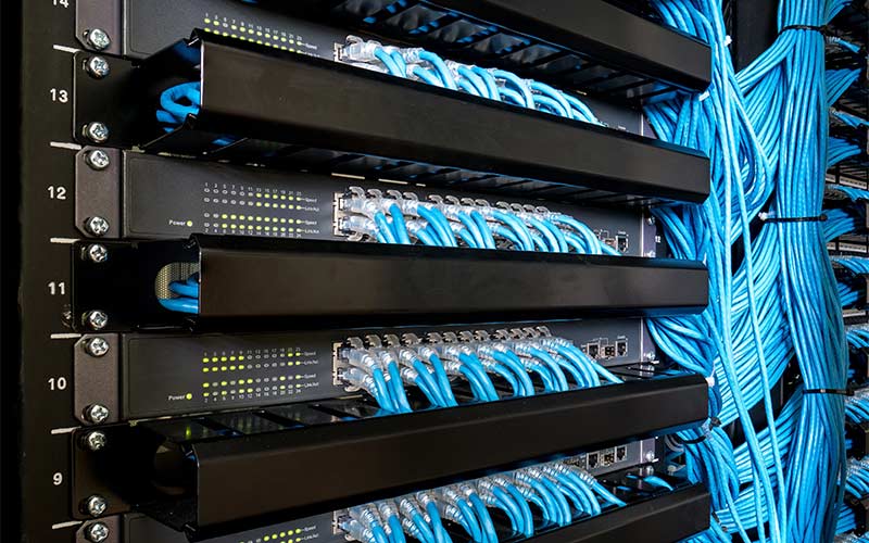 Many network switch hubs and ethernet cables in rack cabinet